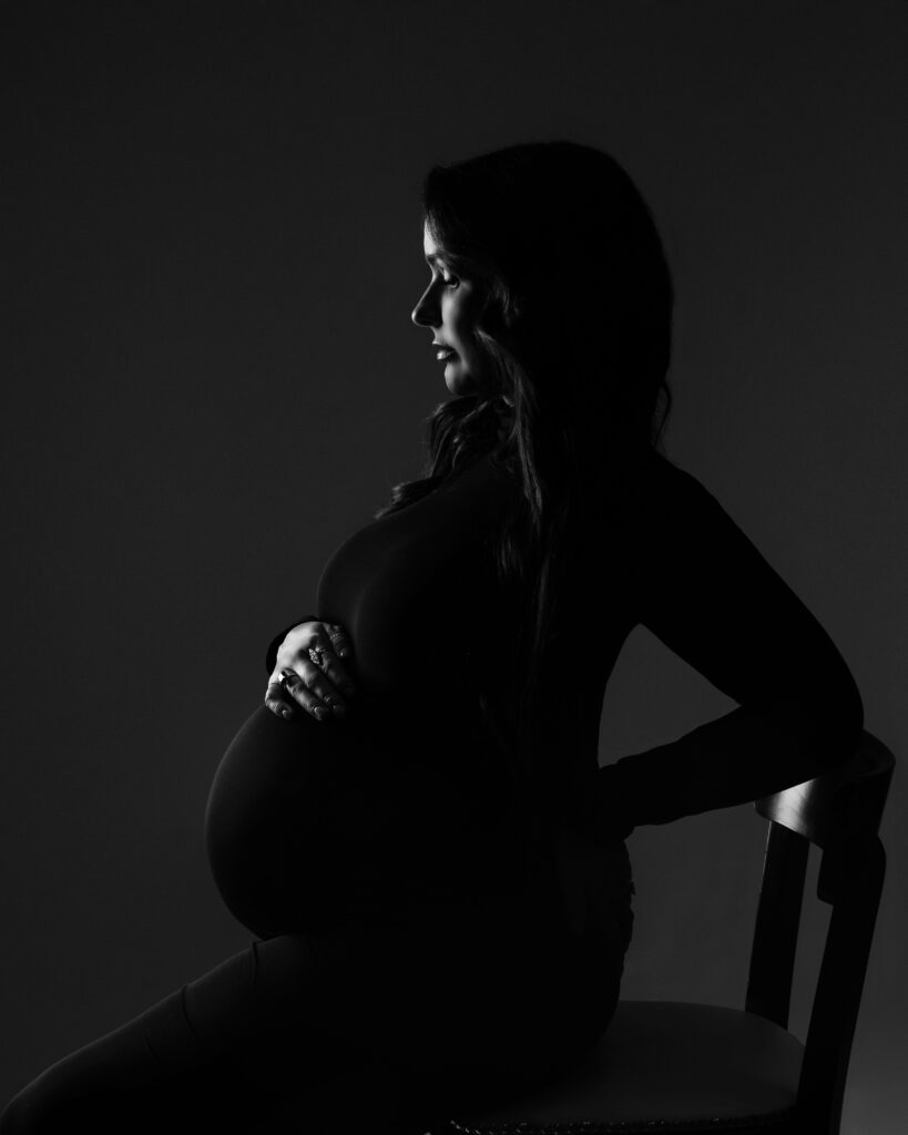 Dramatic low-key maternity silhouette portrait in black and white