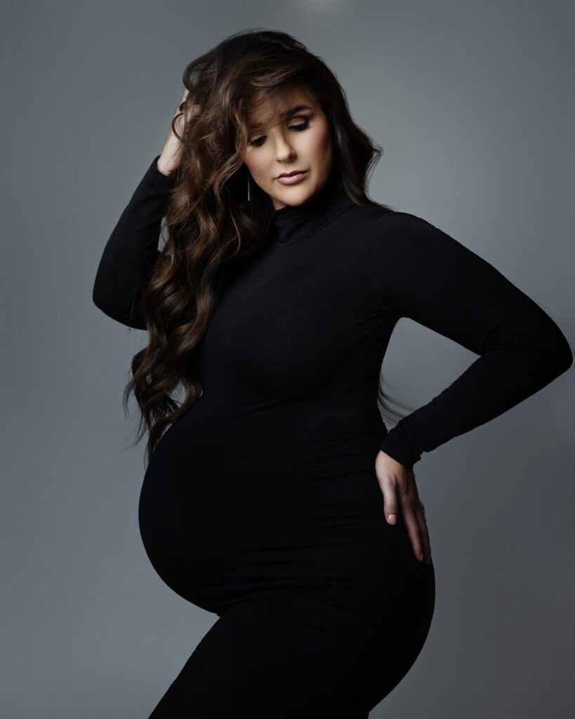 Editorial pregnancy portrait featuring a fitted black maternity dress